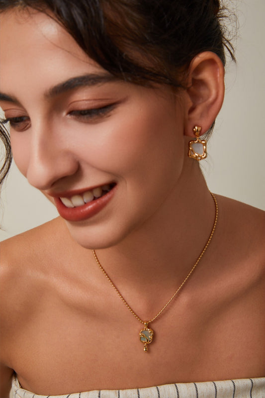 Gold-tone mother-of-pearl heart necklace worn on a model with small drop