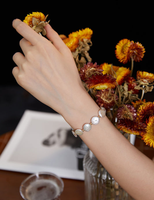 Pearl button bracelet with circular white pearls and gold-tone links on hand
