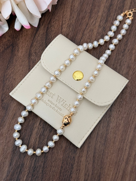 Natural pearl necklace with gold-tone clasp, multi-strand bead design, laid on case
