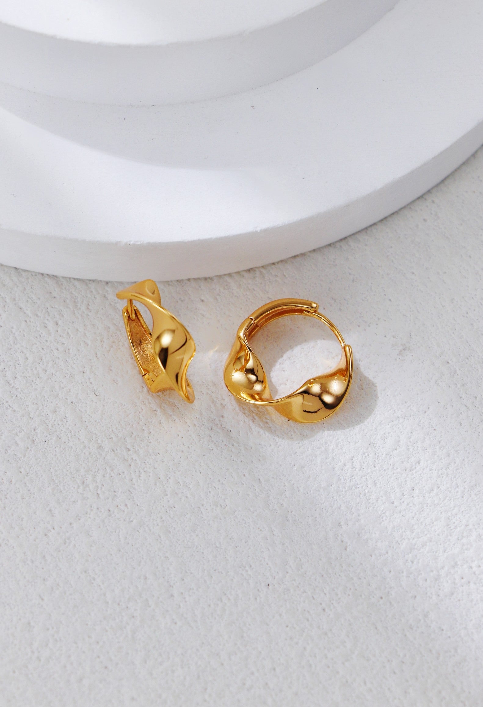 Twisted hoop earrings in gold with small bead-like details on the clasp