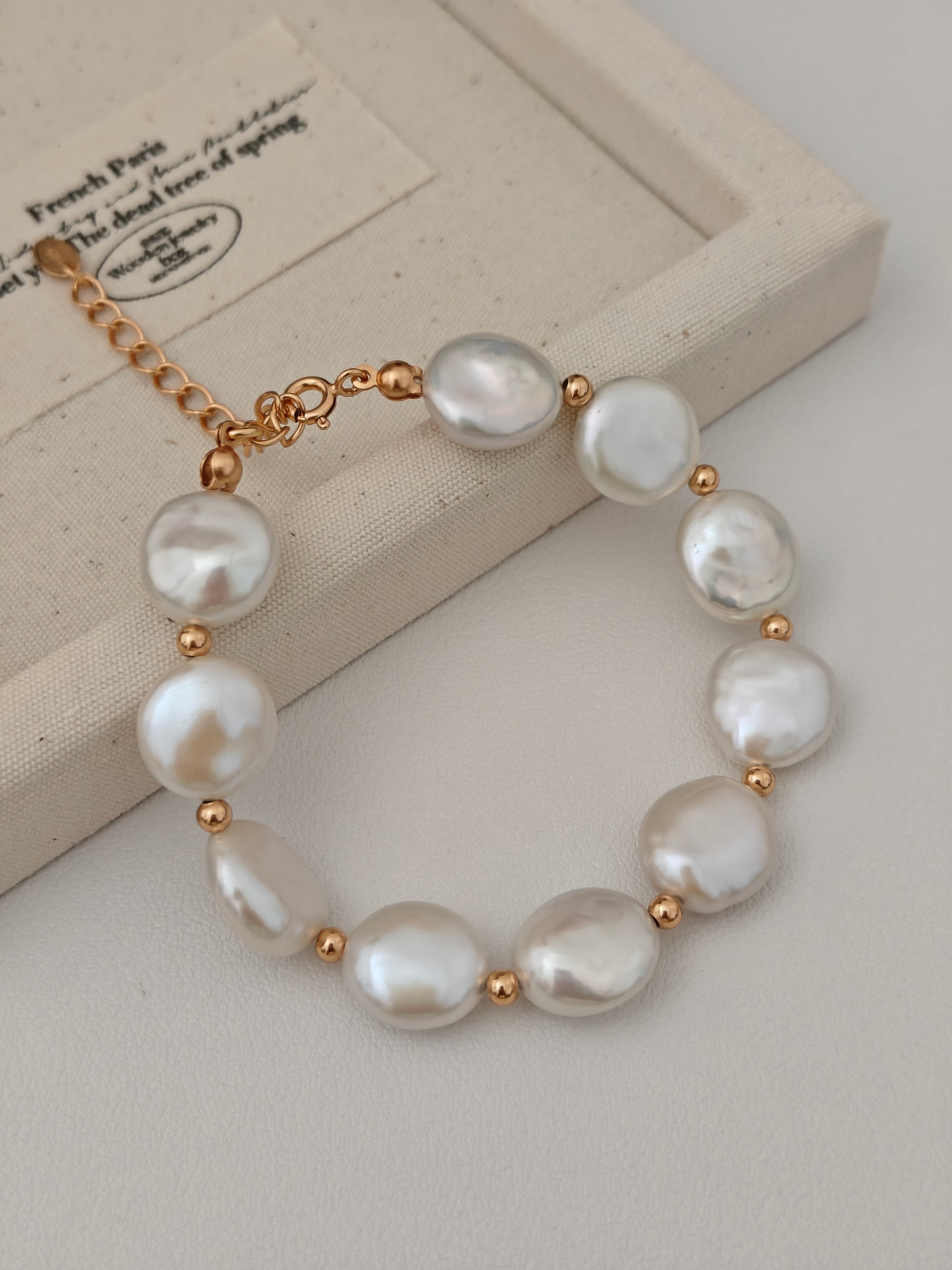 Pearl button bracelet with gold-tone links and white baroque pearls on jewelry card