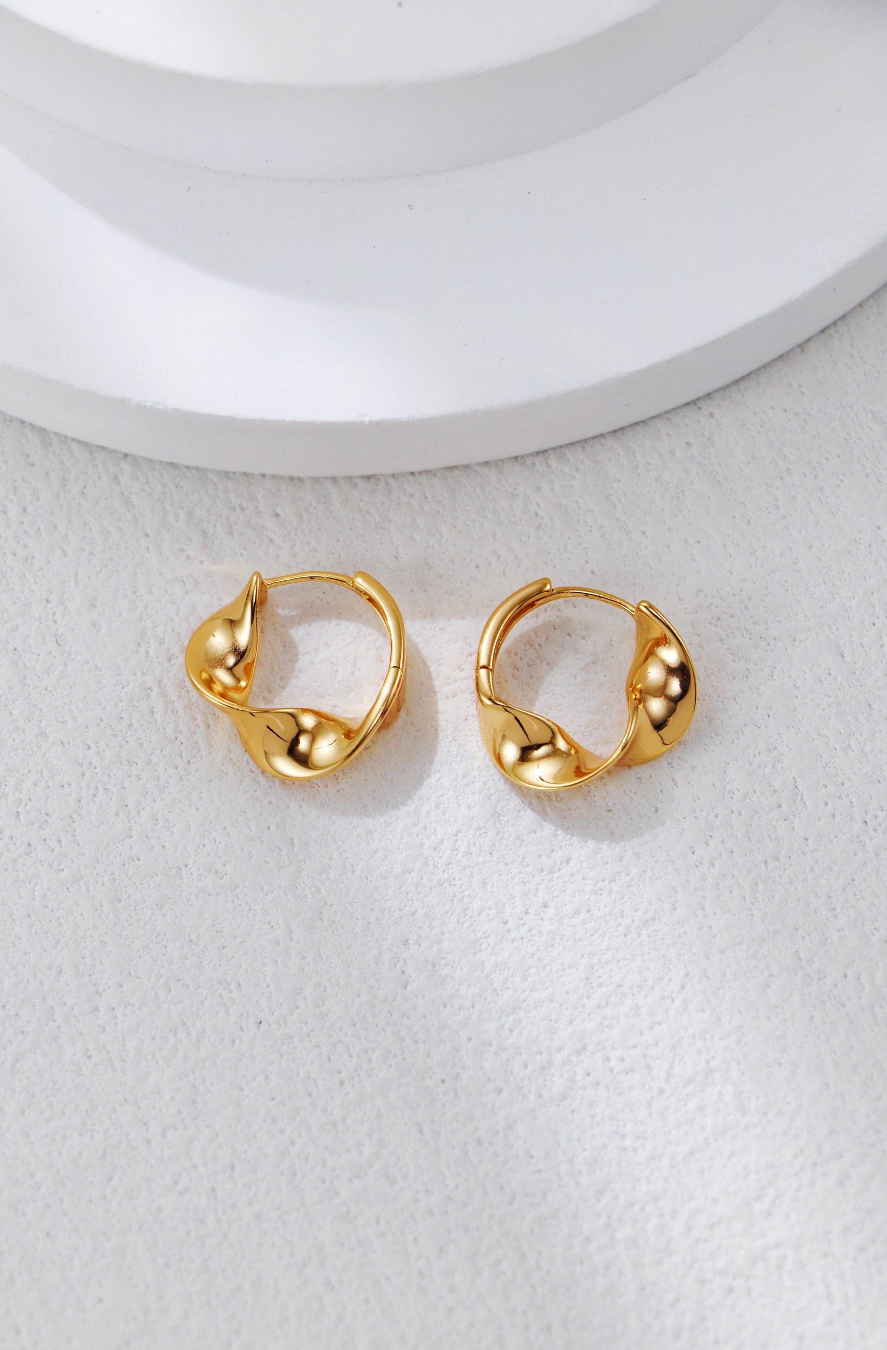 Twisted gold hoop earrings with twisted knot design and small ball accents