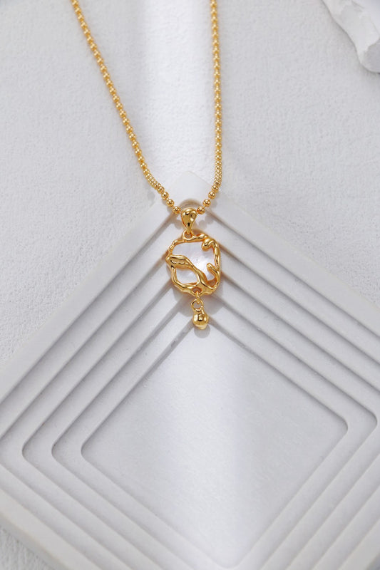 Gold-tone mother-of-pearl heart pendant necklace on textured display