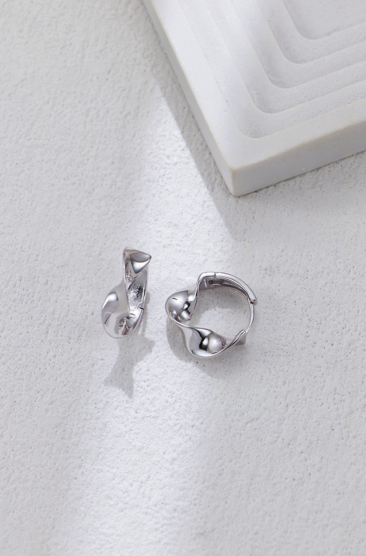 Twisted silver hoop earrings with twisted front and small ball accents
