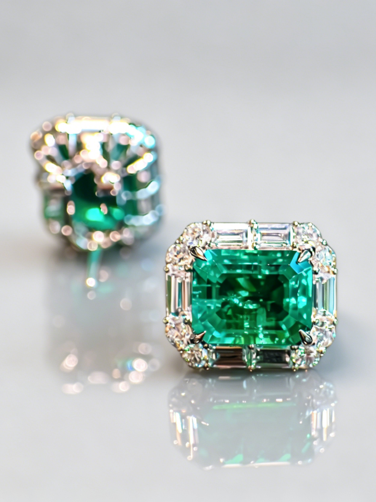 Emerald stud earrings with square emerald centers and diamond halo settings, small prongs