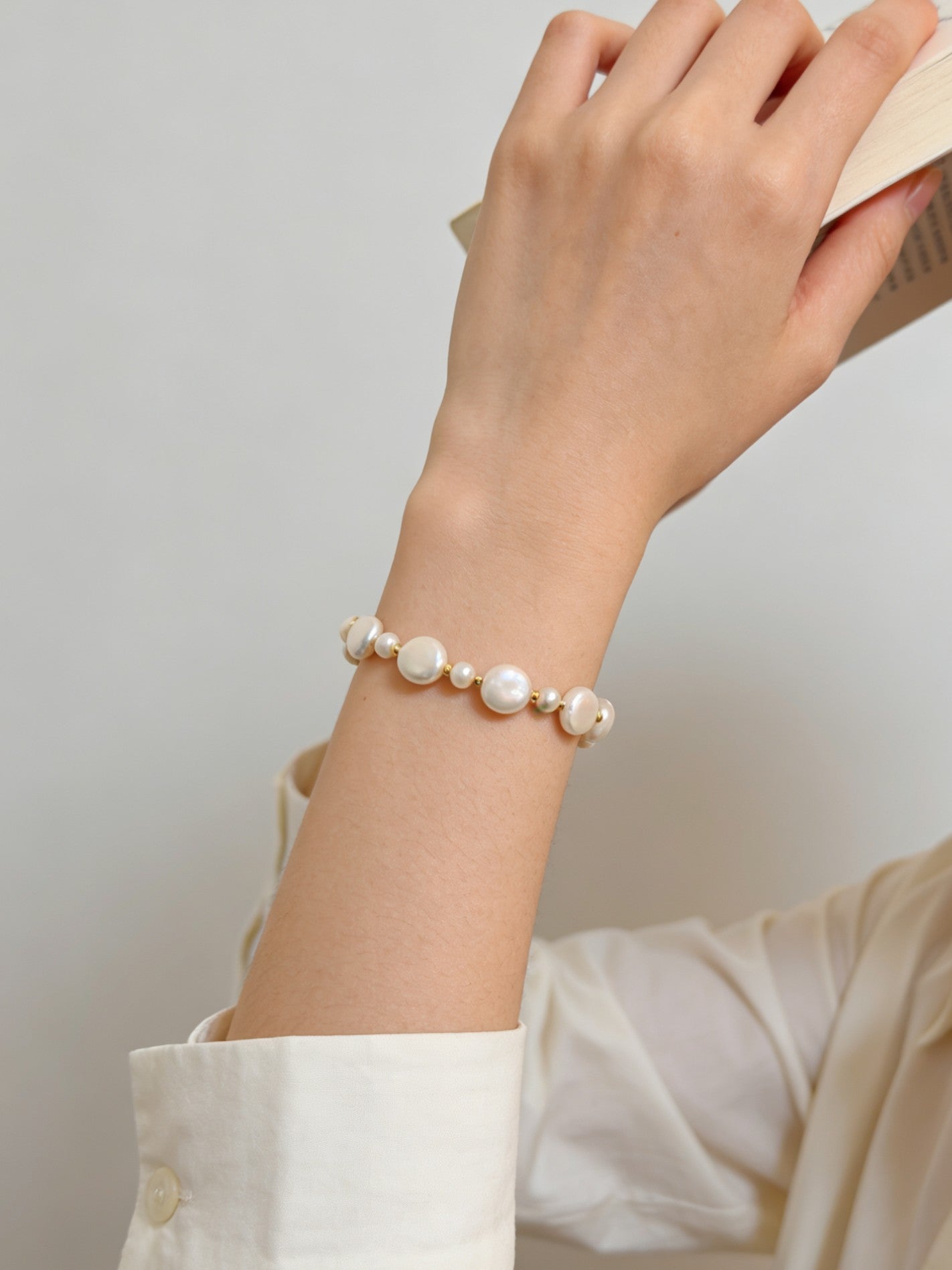 Pearl bead bracelet on wrist with gold-tone chain and white pearls