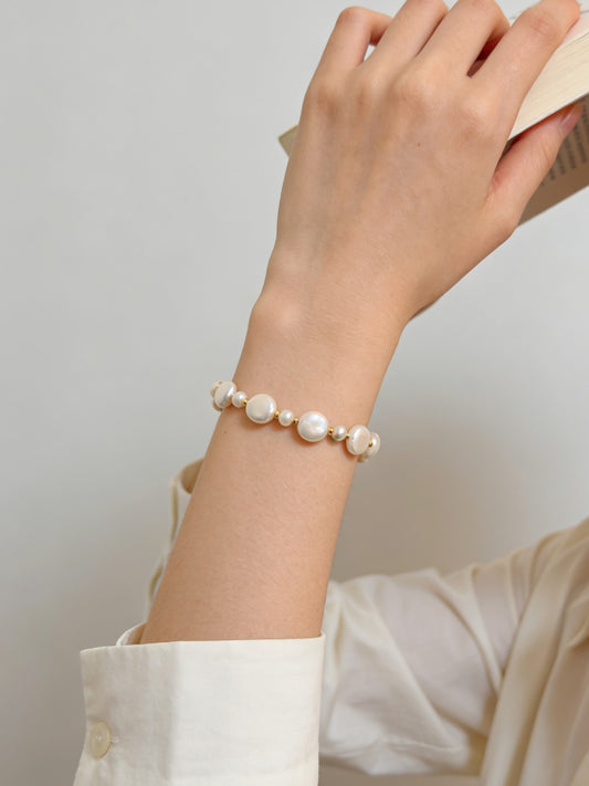 Pearl bead bracelet on wrist with gold-tone chain and white pearls